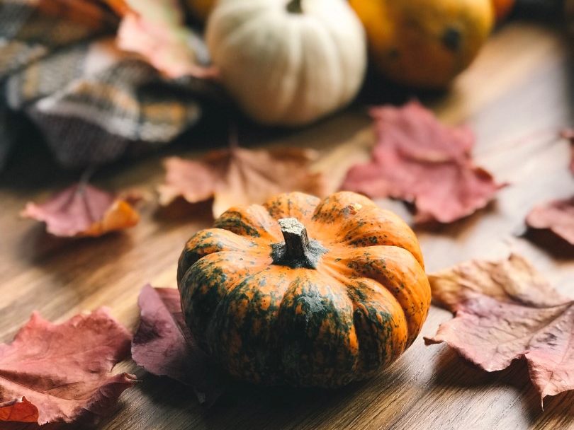 Small pumpkins and leaves on a wood surface.